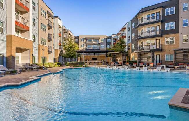 A large swimming pool in front of apartment buildings.