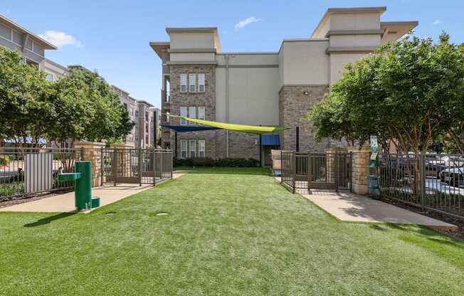 Dog park with a large grassy area and water fountain at GreenVue apartments in Richardson, TX