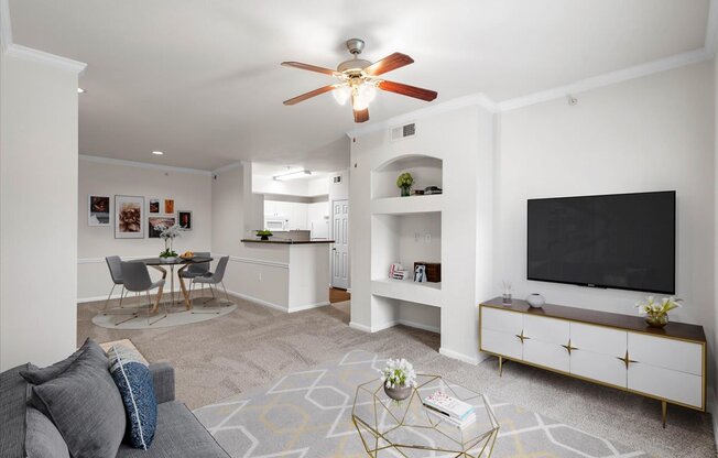 a living room with a ceiling fan and a flat screen tv
