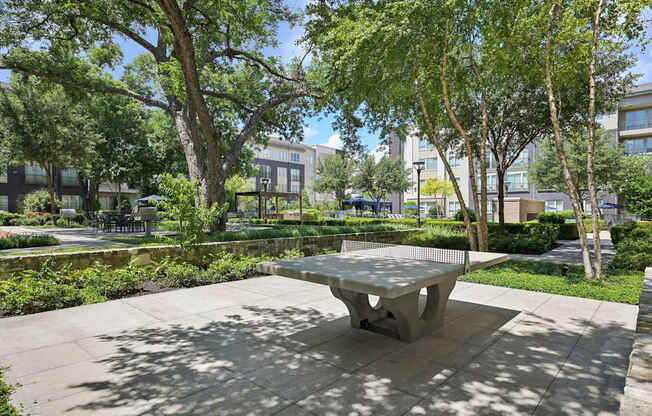 A concrete table is in the middle of a sunny park.