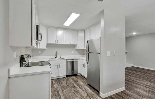 A kitchen with white cabinets and a stainless steel refrigerator.