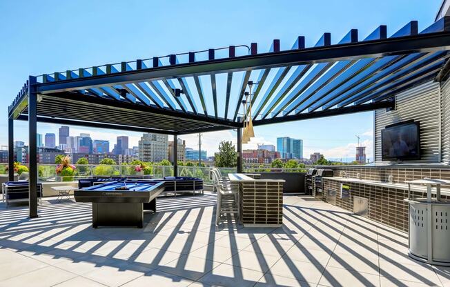 Sky deck at Westend Apartments featuring a full grilling station, billiards table, and island seating covered by a pergola.