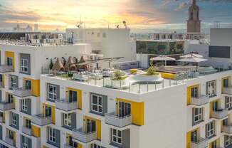 a rendering of a building with a green roof and a sunset in the background