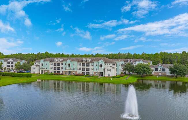 a fountain in the middle of a lake with houses in the background