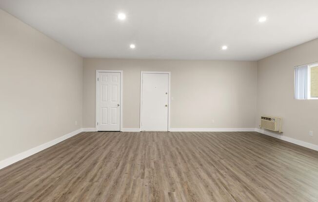 a bedroom with a hardwood floor and white walls