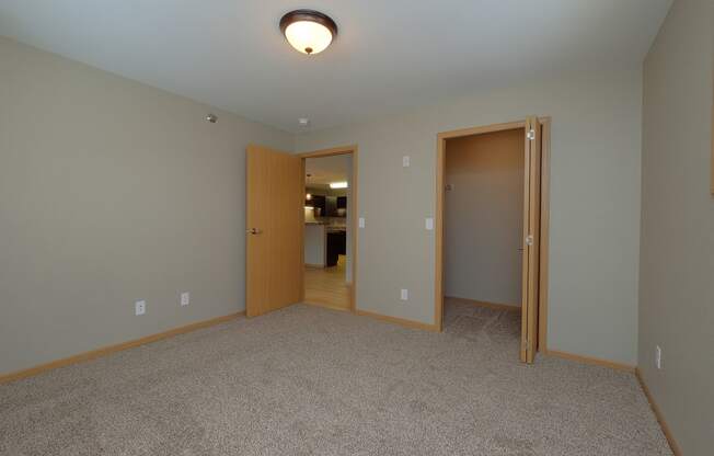 a bedroom with a door to a bedroom and a closet. Fargo, ND Urban Plains Apartments