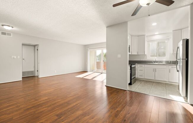 A spacious kitchen with white cabinets and a wooden floor.