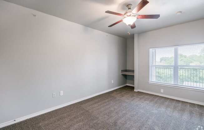 an empty living room with a ceiling fan and a window