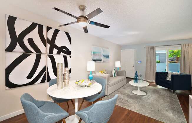 a living room with a ceiling fan and a table and chairs