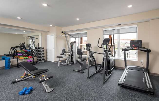 a gym with treadmills and other exercise equipment in a room with windows