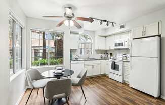 A kitchen with white appliances and a table with chairs.