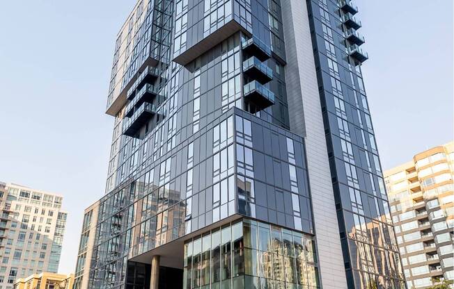 A modern glass building with a curved design stands tall among other buildings.