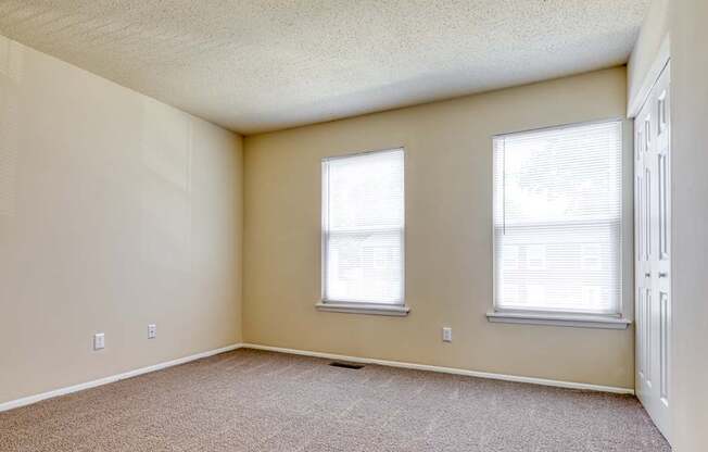 A room with two windows and a carpeted floor.