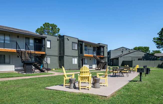 outdoor patio at fusion fort worth apartments with lawn, barbecue, and yellow patio furniture