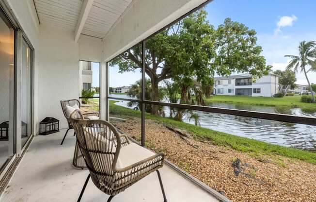 a balcony with a wicker chair and a view of a body of water