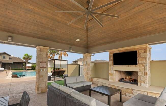 the estates outdoor living area with fireplace and tv