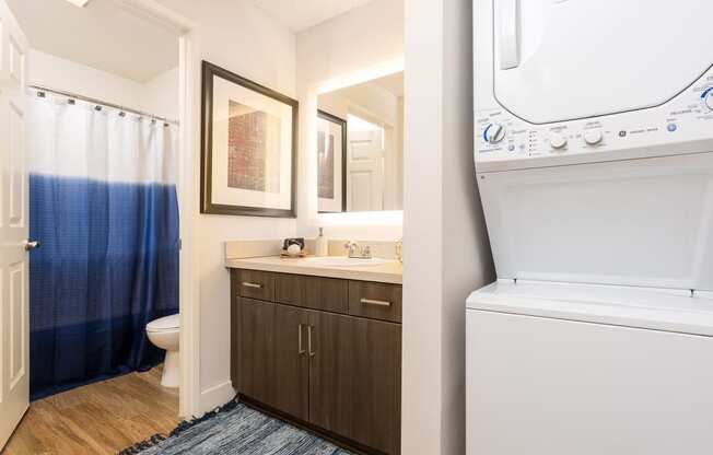 a white washer and dryer in a bathroom next to a sink and toilet