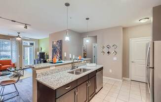 A kitchen with a sink, refrigerator, and a counter with a bowl on it.