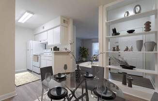 A modern kitchen with a glass dining table and chairs.
