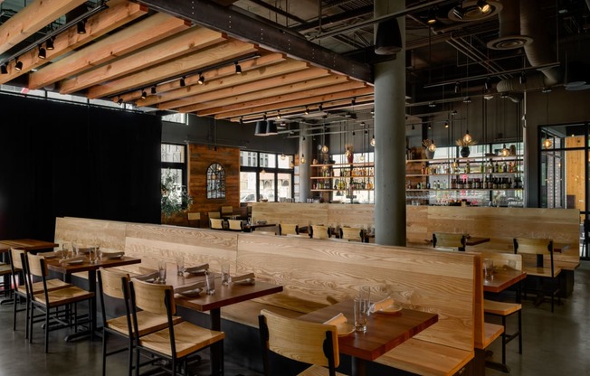 a restaurant with wooden tables and chairs and a bar at The Lucy Boise Apartments, Boise