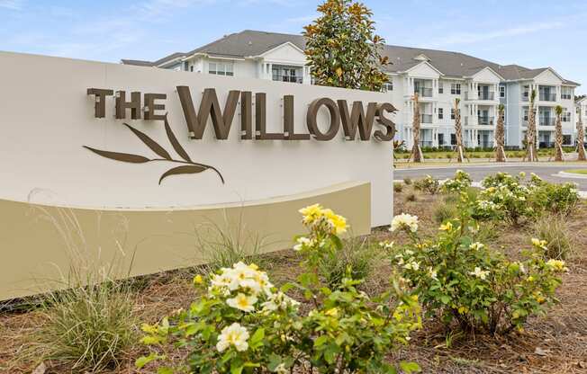a sign for the willows with flowers in front of a building