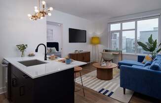 A modern kitchen with a blue sofa and a TV mounted on the wall.