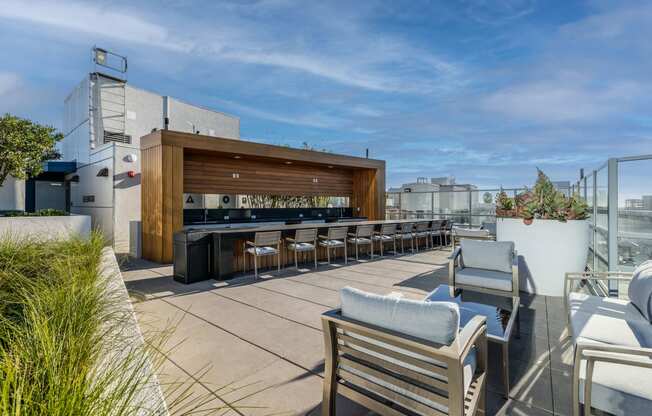 a rooftop patio with a bar and chairs and furniture