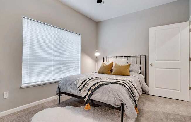 a bedroom with a bed next to a window. Circle Pines, MN Lexington Lofts