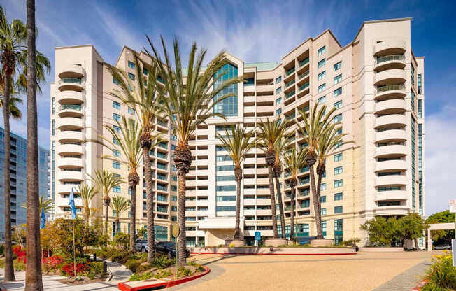 A large building with palm trees in front of it. at Towers at Costa Verde Apartments, San Diego, California