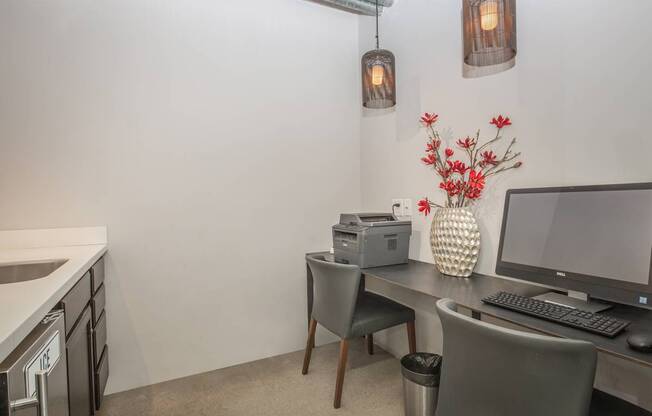 A small office with a desk, chairs, and a computer.