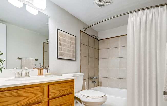 Bathroom with white tile tub and updated vanity in Aurora one-bedroom apartment.