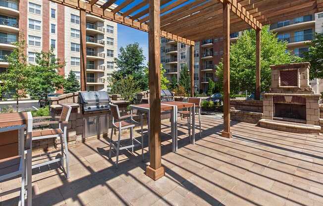 A wooden pergola with a fireplace is in the middle of a patio.