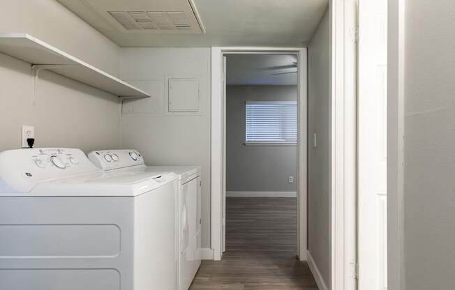 A white washing machine in a small room with a door open to a hallway.