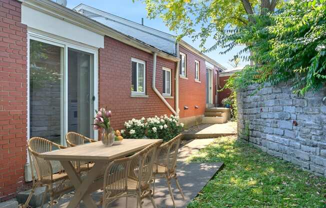 a patio with a table and chairs in front of a brick house