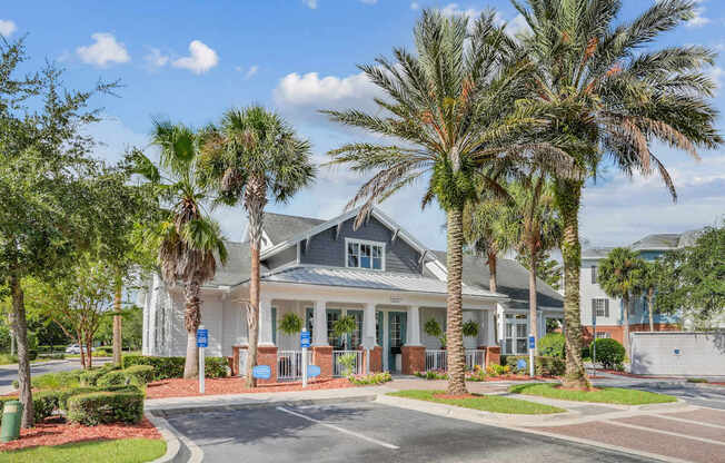 A leasing office with a grey roof is surrounded by palm trees at Wynnfield Lakes Apartments in Jacksonville, FL