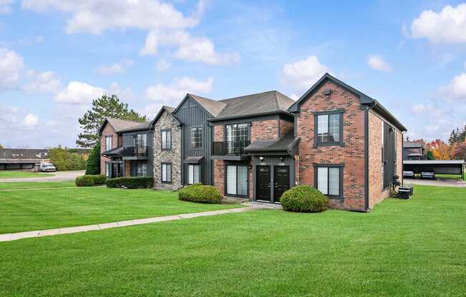 A large house with a black roof and a green lawn in front.