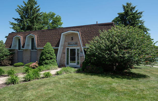 brick leasing office with a grassy yard and a tree