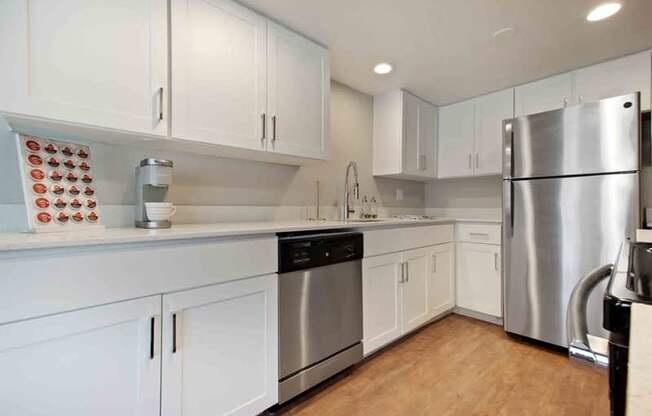 A kitchen with white cabinets and a stainless steel refrigerator.