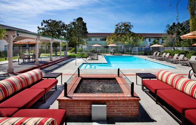 a pool with red and white lounge chairs and a swimming pool