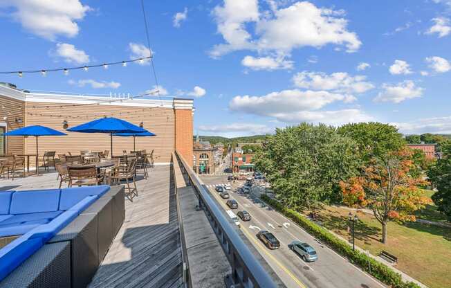 a rooftop patio with tables and umbrellas and a street with cars at The Merc, Waltham, 02453