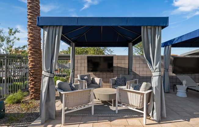 A patio with a blue canopy and wicker furniture.