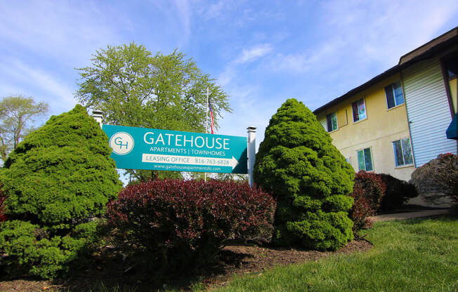 a building with a gatehouse sign in front of bushes and trees