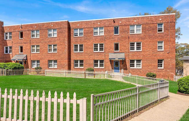 A red brick building with a white picket fence in front at Highland Ridge Apartments, Capitol Heights, Maryland