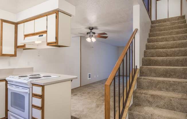 the kitchen is next to the stairs in a home with a ceiling fan