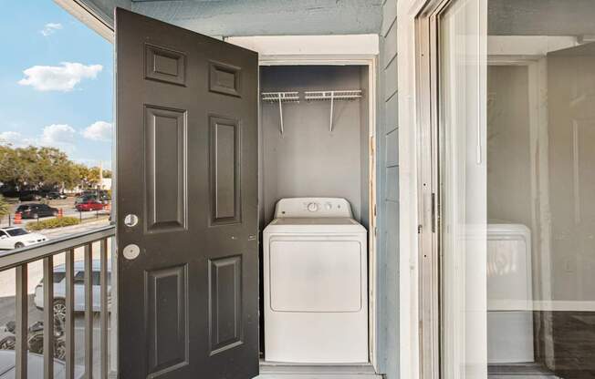 A white washing machine and dryer are in a small outdoor laundry room.