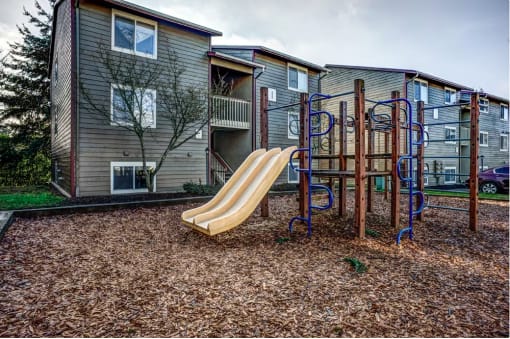 a slide at a playground in front of an apartment building