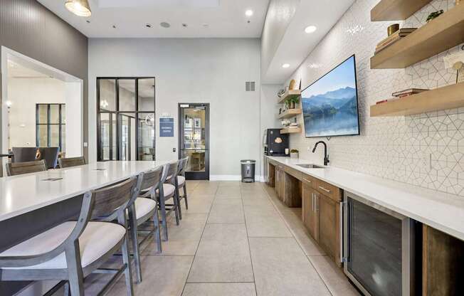 A modern kitchen with a long counter and chairs.