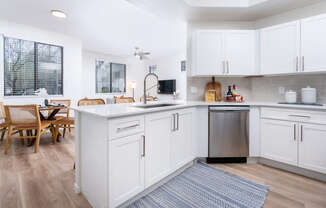 A kitchen with white cabinets and a wooden table.