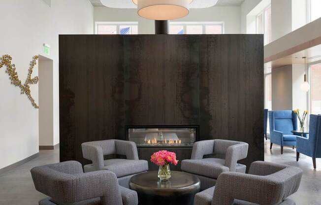 A living room with a fireplace and grey chairs.