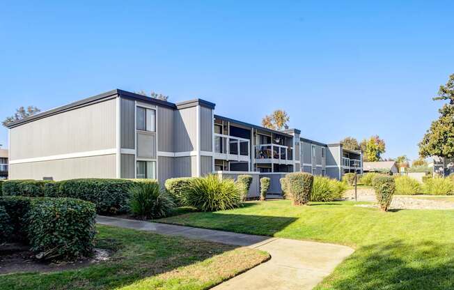 A modern building with a grey facade and a green lawn in front.